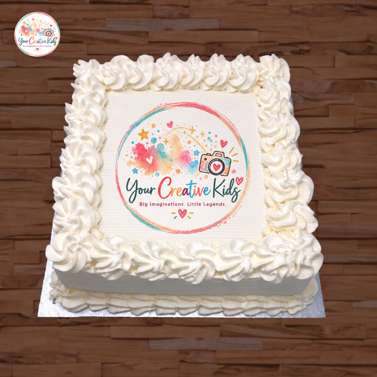 A plain white cake finished with the colourful Your Creative Kids logo